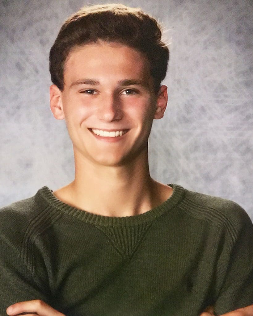 Smiling young man in a green sweater portrait.