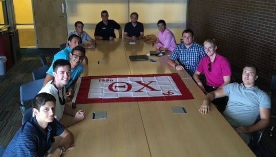 Group meeting with fraternity flag on table.