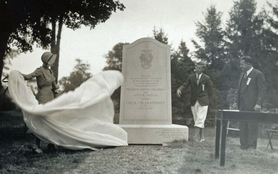 Historical figure unveiling a monument in a cemetery.