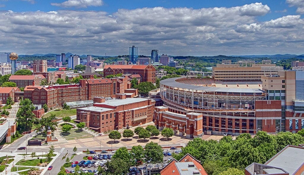 University campus with stadium and city skyline.