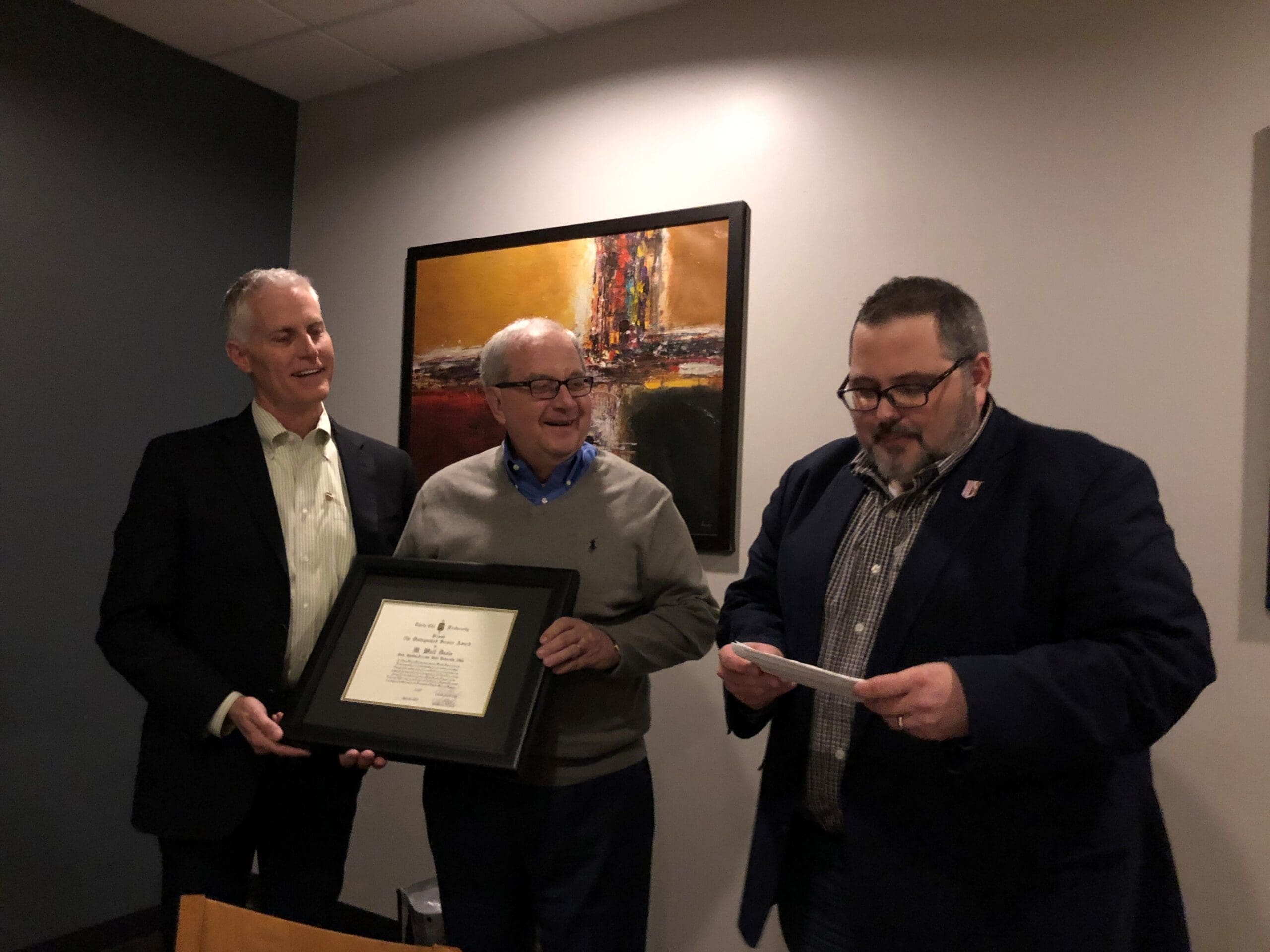 Three men celebrating an award presentation event.
