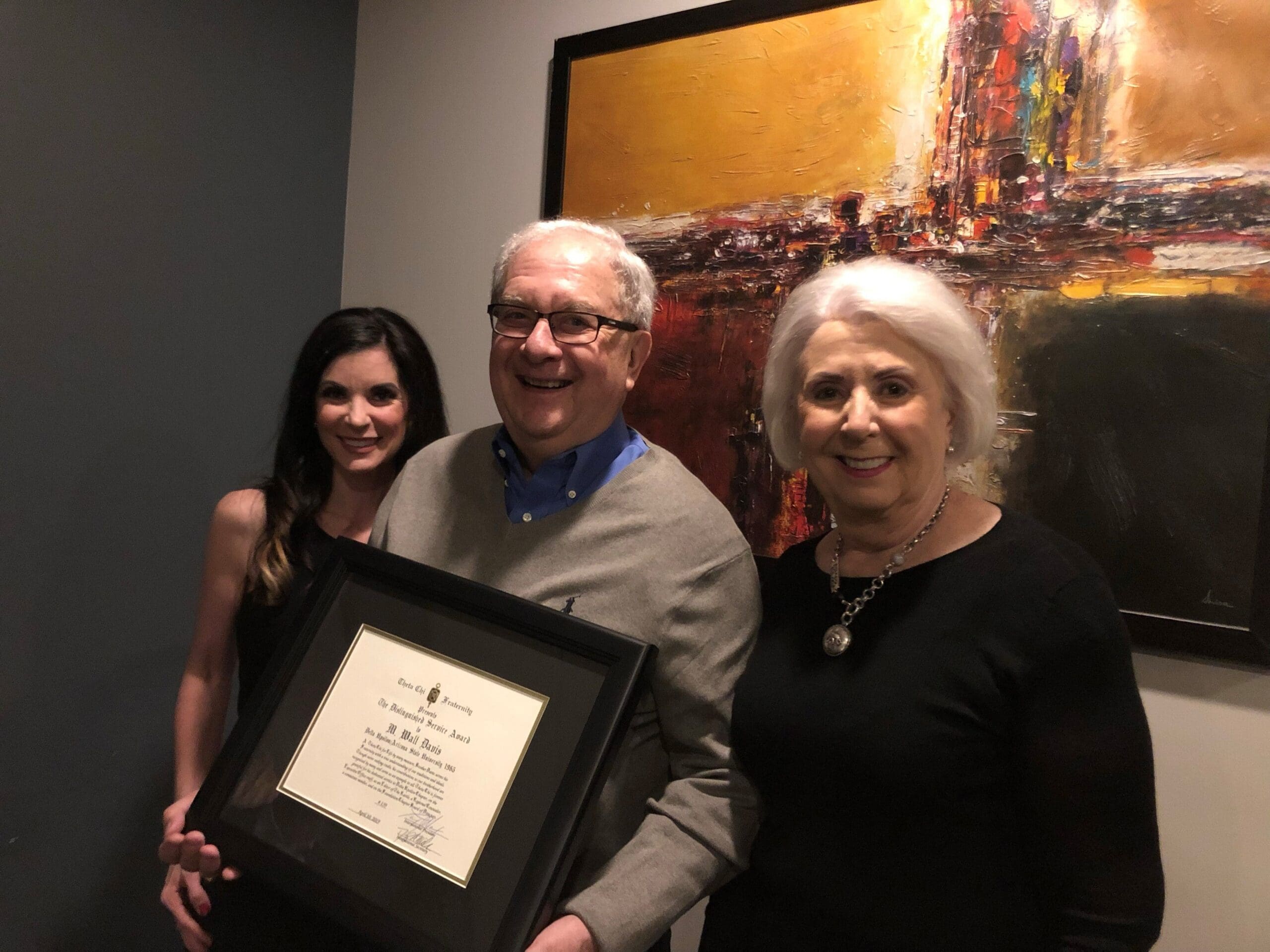 Three people proudly displaying an award certificate.