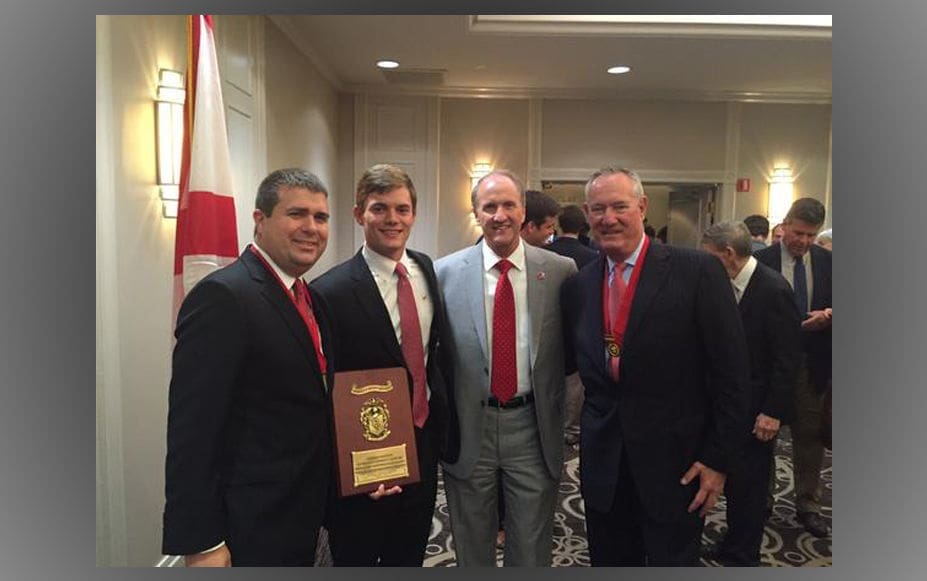 Group of men at an awards ceremony holding plaque.