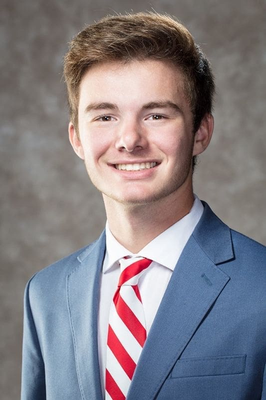 Smiling young man in a blue suit and tie.