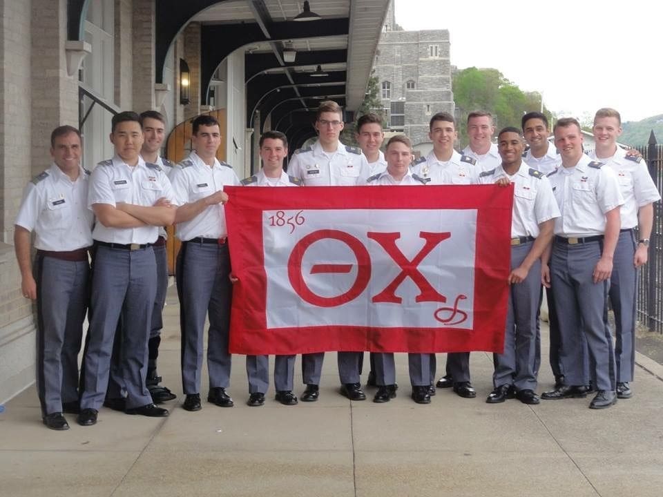 Cadets holding fraternity flag on campus.