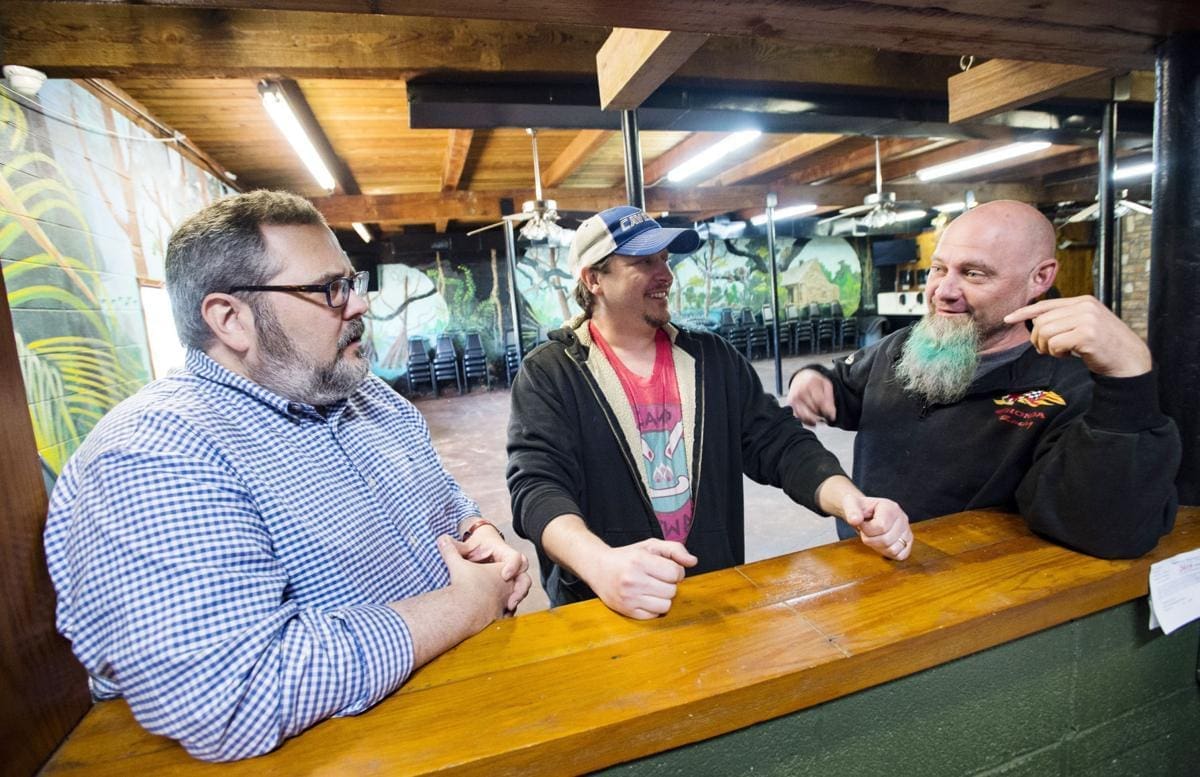 Three men engaging in conversation at a bar.
