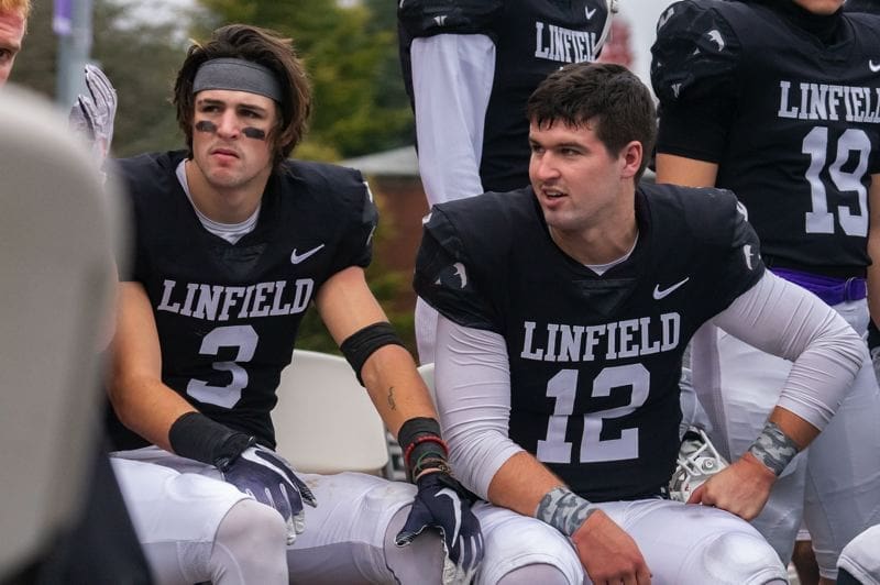 Wyatt Smith Linfield football players on bench during game.