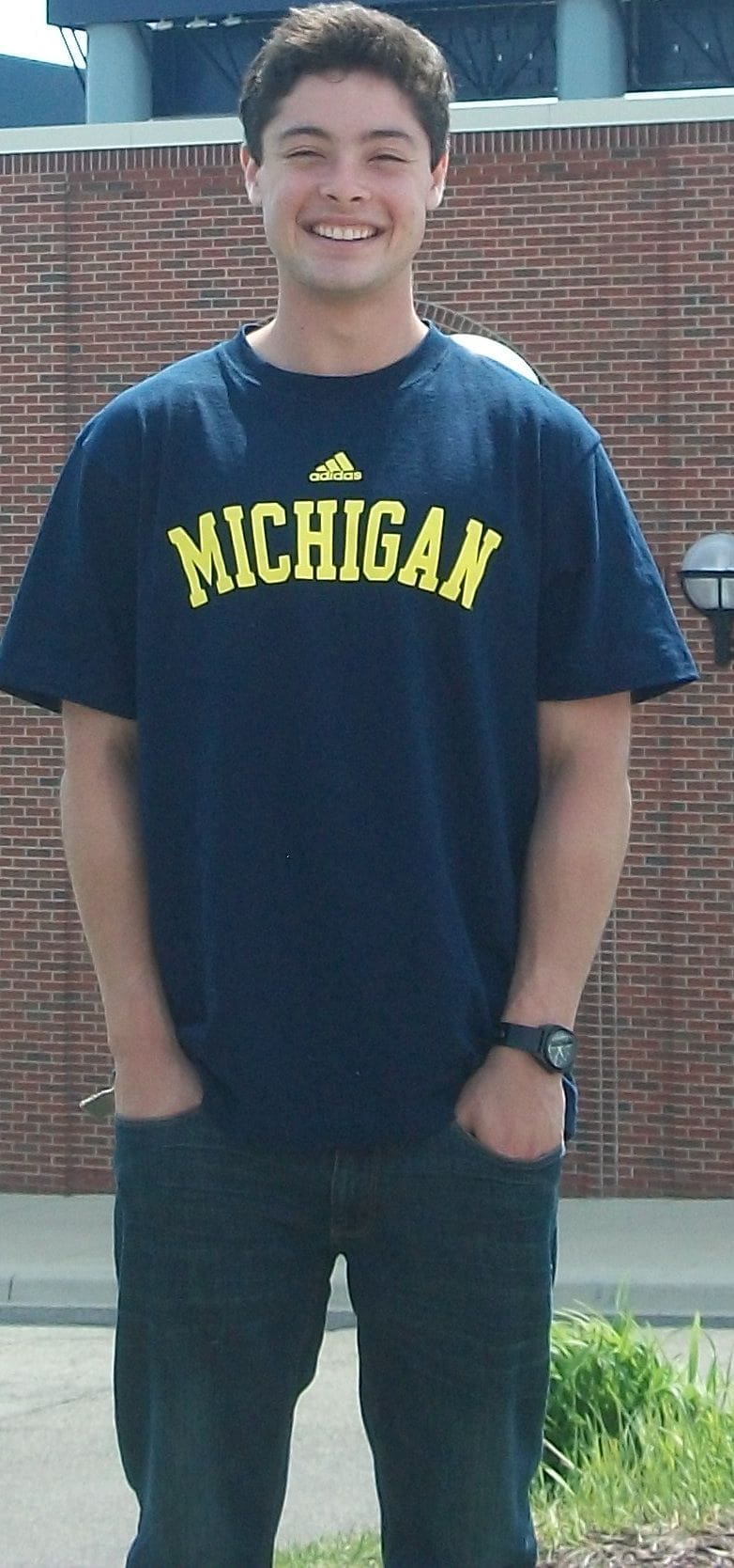 Person wearing Michigan Adidas t-shirt outdoors.