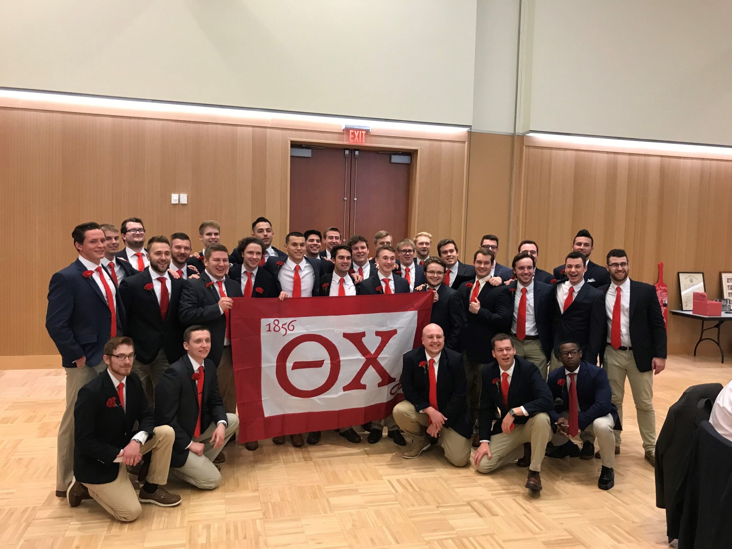 Group of fraternity members posing with flag.