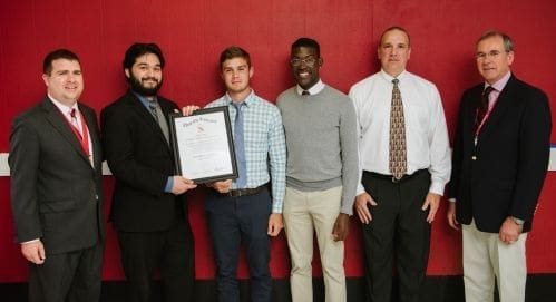 Four men holding an award certificate together.