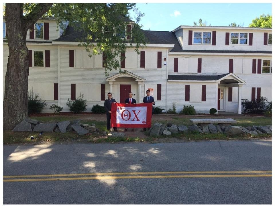 Three people holding a flag in front of a building.