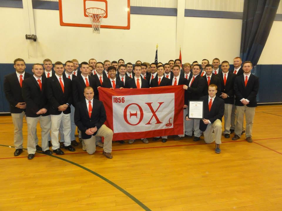 Group of young men with fraternity flag in gym.
