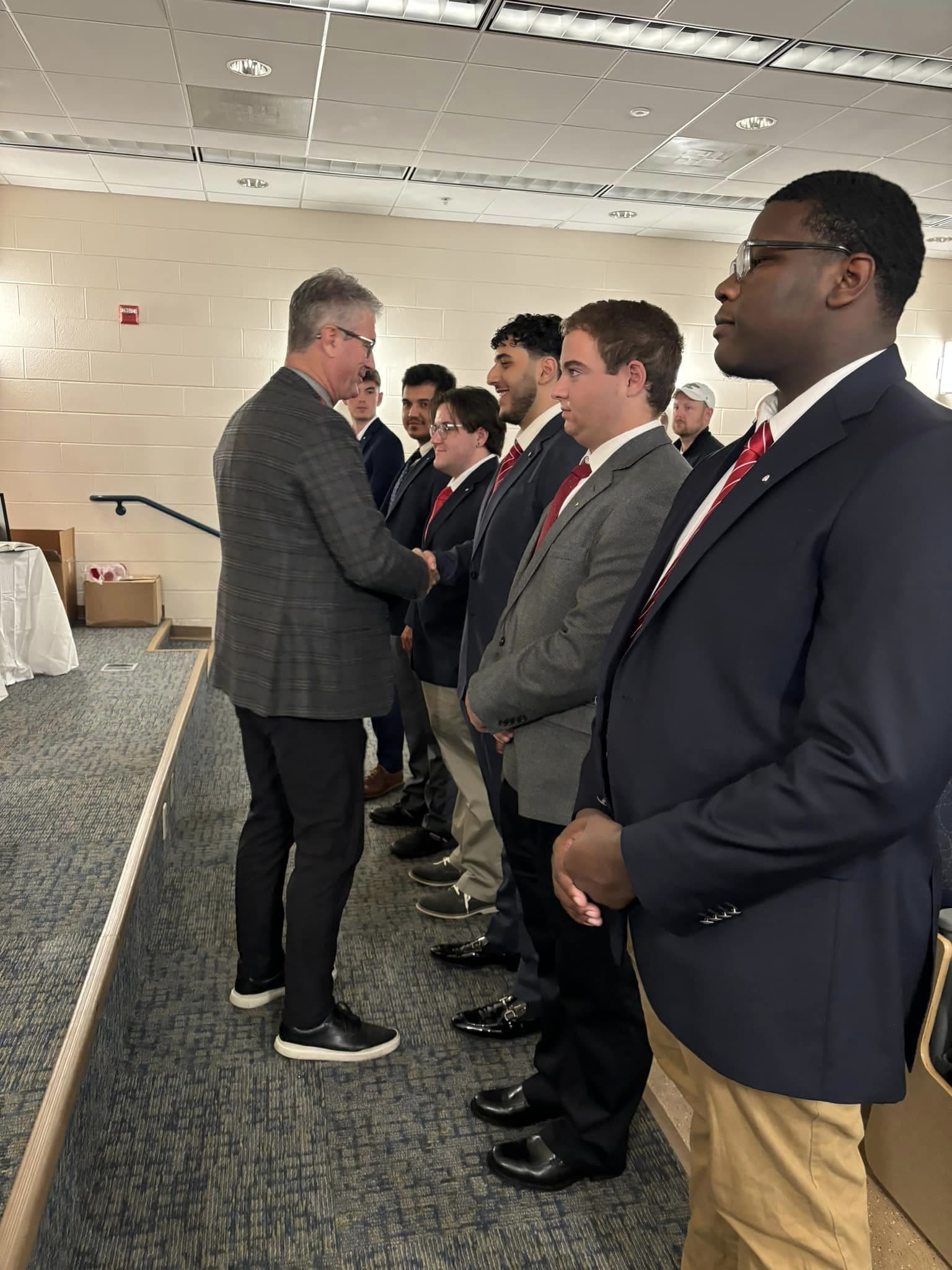 Men in suits at a formal event shaking hands.