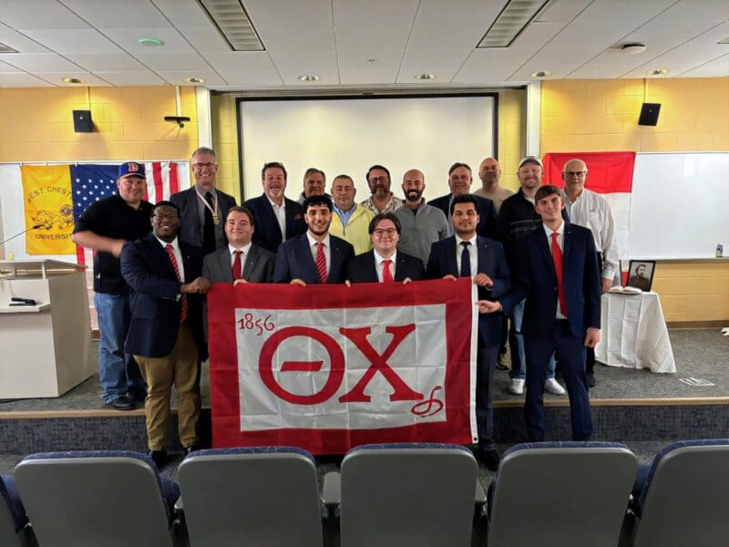 Group photo with fraternity flag and members.