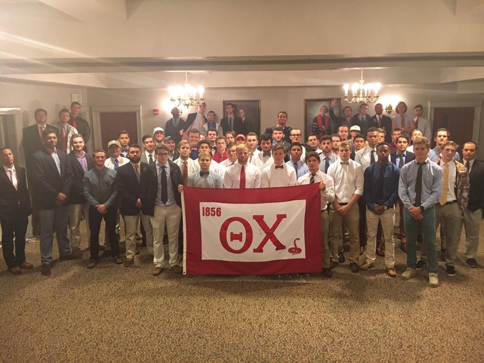 Group photo of fraternity members with banner.