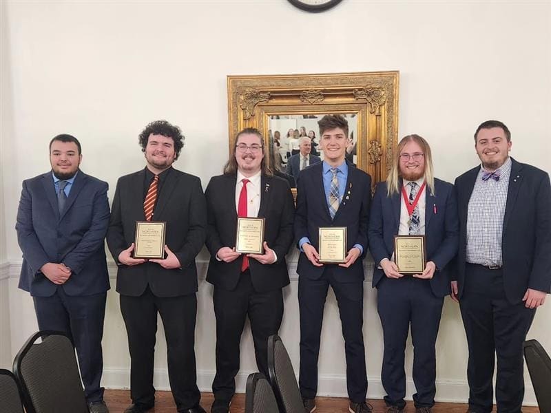 Group of award recipients holding plaques at ceremony.