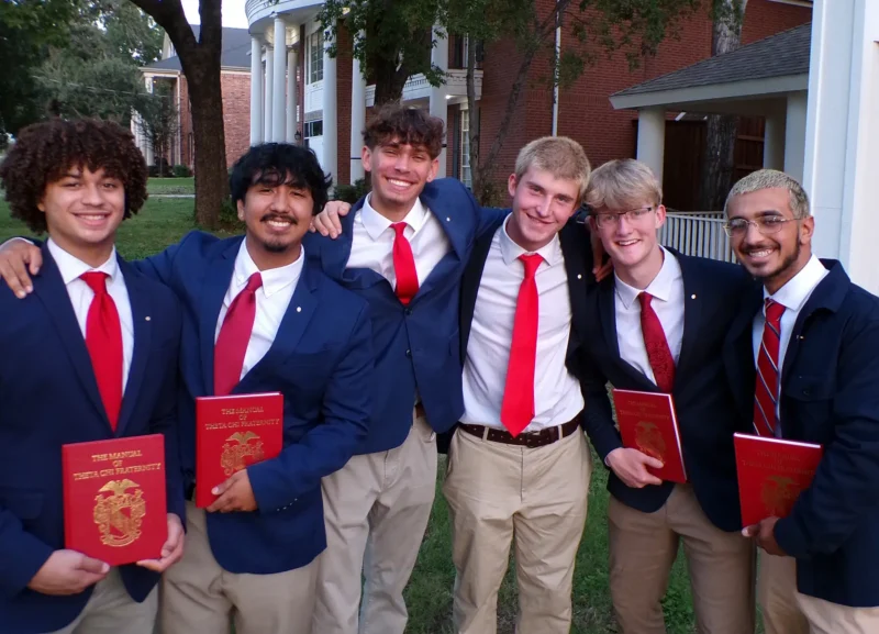group of brothers holding the Manual of Theta Chi