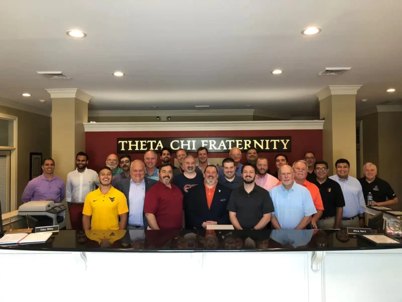 a group of Theta Chi in front of a sign
