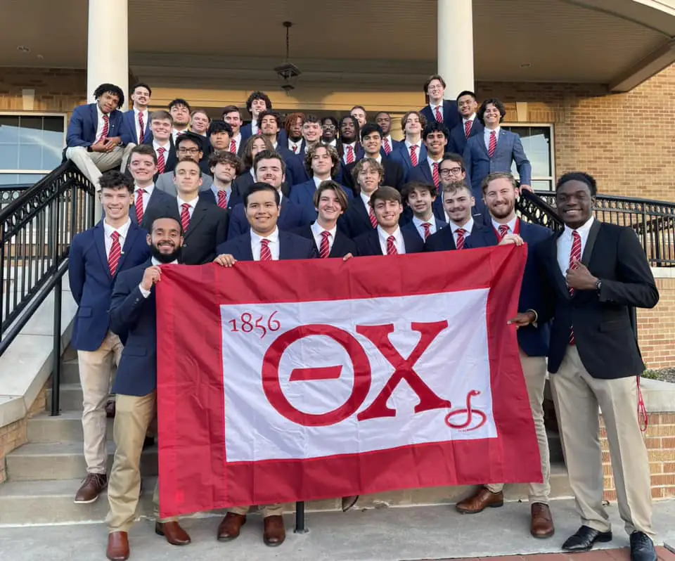 group of Brothers holding a flag on stairs outside