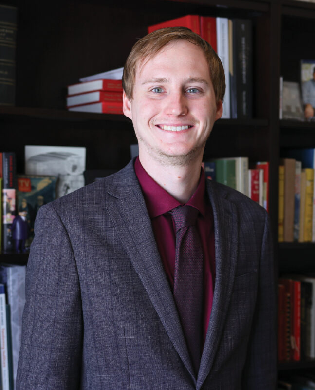 Photo of a man in a suit in front of a bookcase