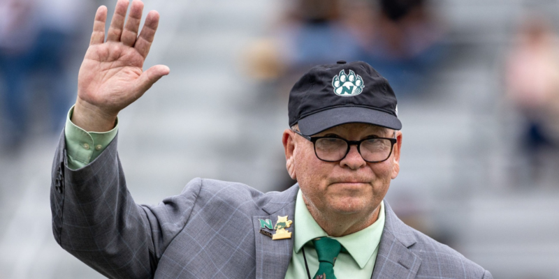 A man waving with glasses and a hat on