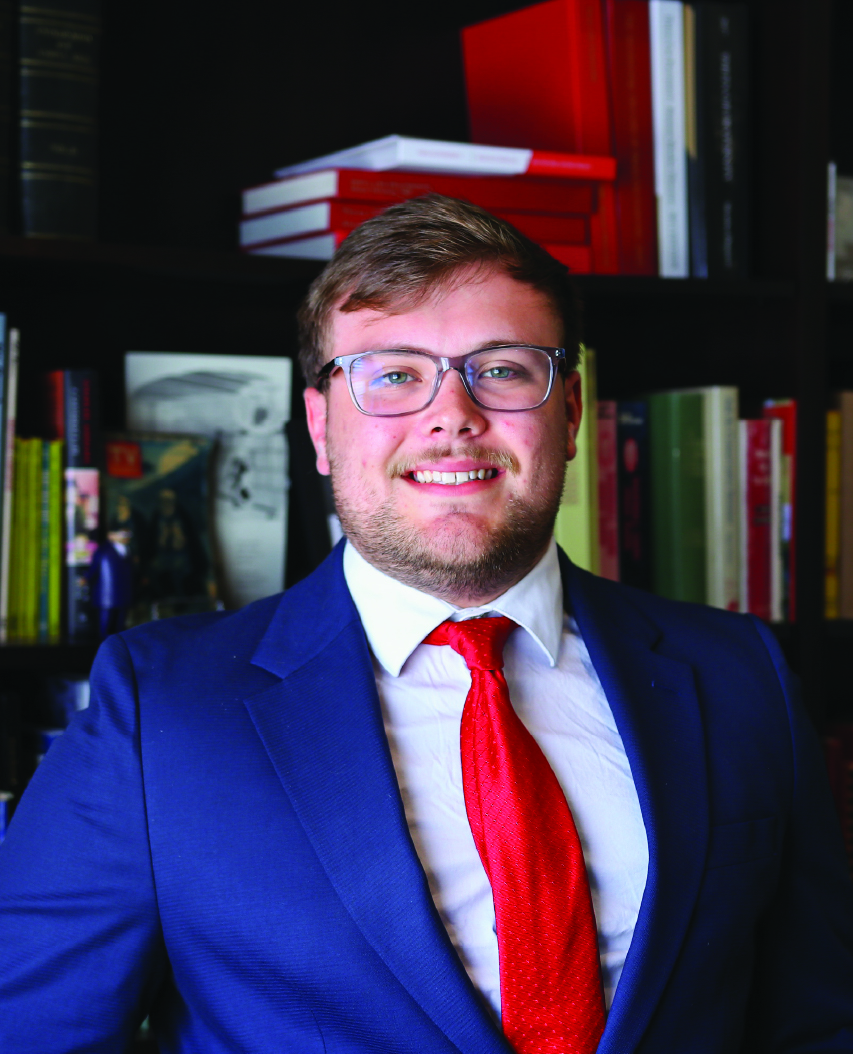 Photo of a man in a suit in front of a bookcase
