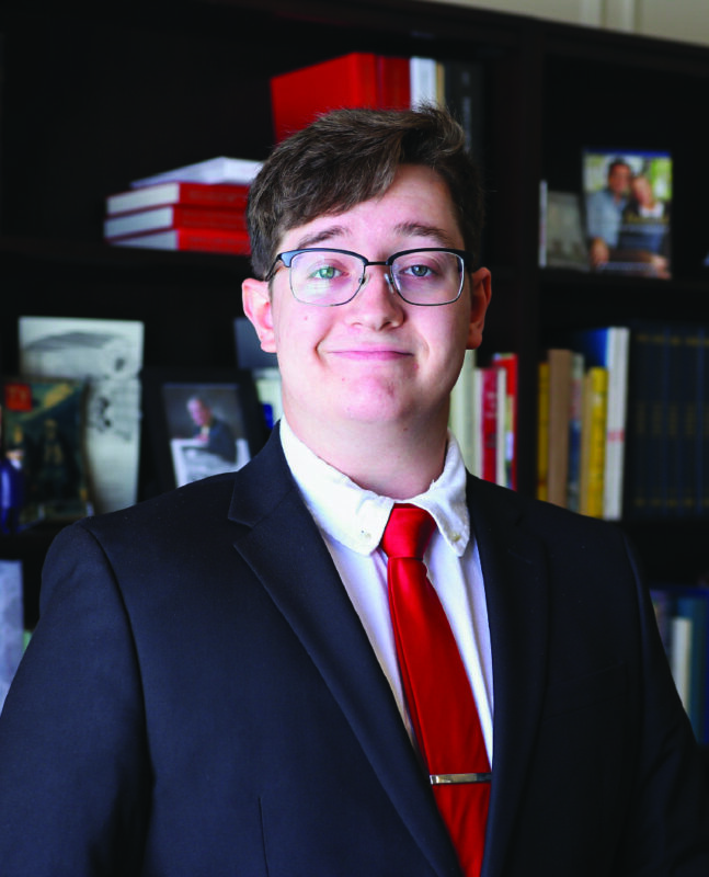 Photo of a man in a suit in front of a bookcase