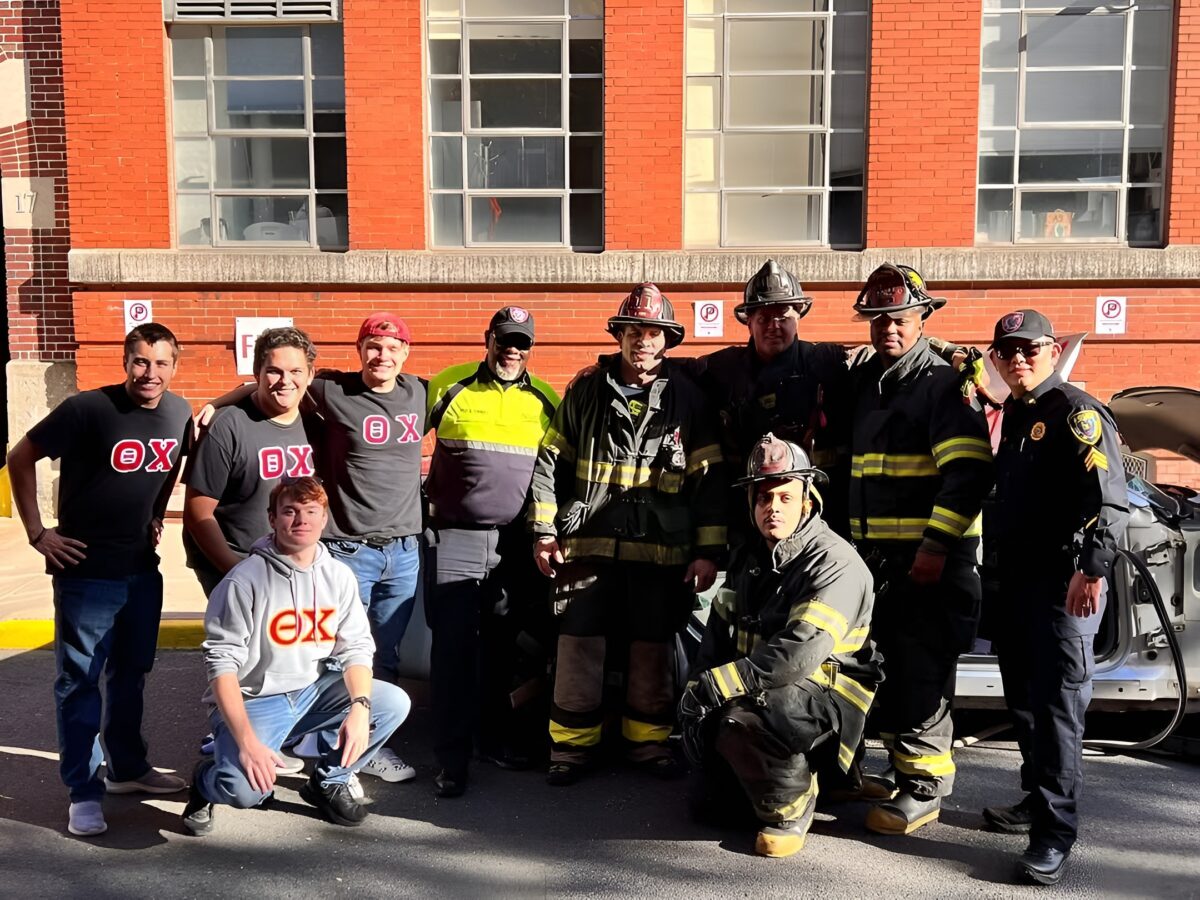 Firemen and college students standing and kneeling together