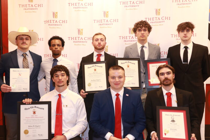Men sitting together holding various awards