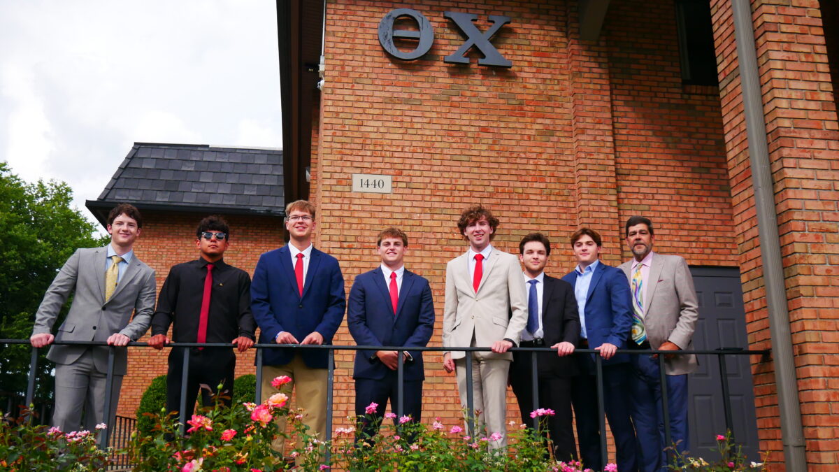 Men in suits standing in front of the Alpha Iota/Indiana Chapter House