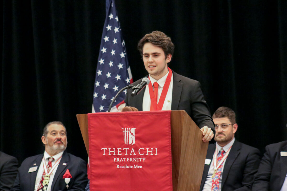 Man standing at a Theta Chi Fraternity branded podium