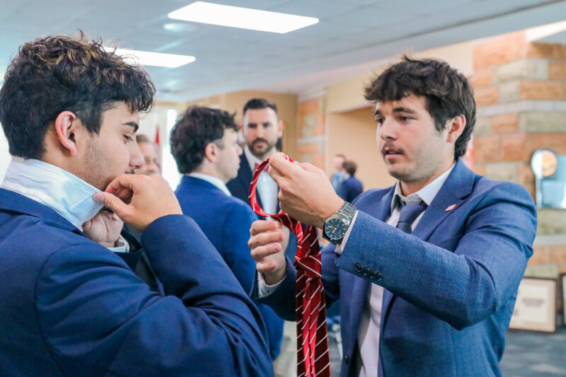 Staff member assisting a collegian with their tie