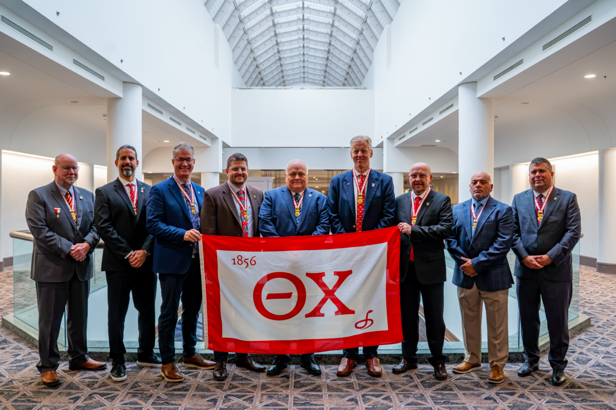 The Grand Chapter standing together with a Theta Chi Flag
