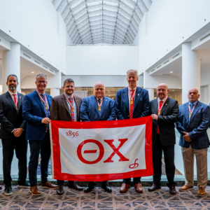 The Grand Chapter standing together with a Theta Chi Flag