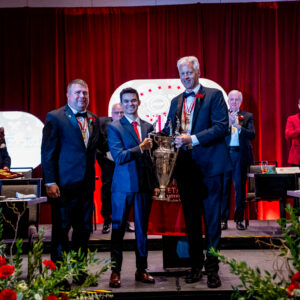 Missouri State's Carlos Abrams holding the Colley Trophy alongside Past Colley Award winners, Mike Mayer and Tom Thompson.
